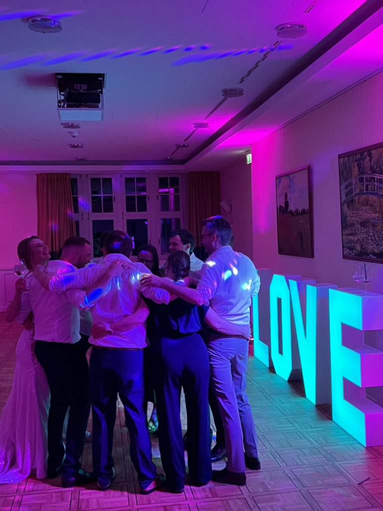 XXL Leuchtbuchstaben "LOVE" im Hintergrund mit tanzender Menge bei Hochzeitsfeier