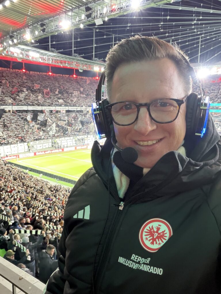 DJ mcJay mit Headset als Reporter Inklusives Fanradio für Eintracht Frankfurt im Deutsche Bank Park mit der Fankurve im Hintergrund